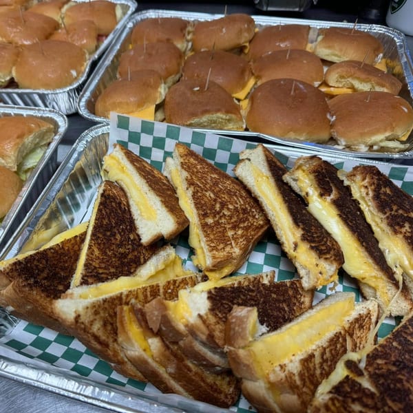 Trays of grilled cheese sandwiches and slider sandwiches with cheese, ready for catering.