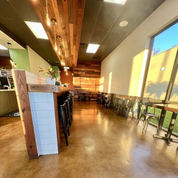 Interior of Rocket Bagels Deli & Catering with a long counter, bar stools, and dining tables.