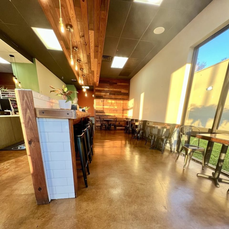 Interior of Rocket Bagels Deli & Catering with a long counter, bar stools, and dining tables.
