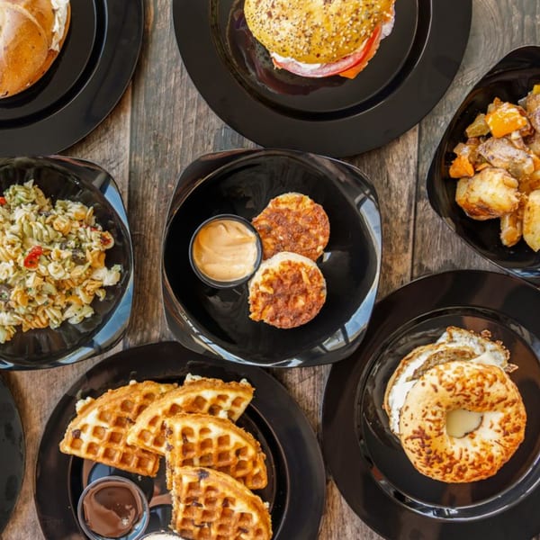 Overhead view of various Rocket Bagels Deli & Catering dishes, including bagels, waffles, and pasta salad.